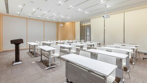 A conference room with white tables, chairs, a podium, and a projector. - Ji Hotel Shanghai Songjiang Sports Square Center (Shanghai)
