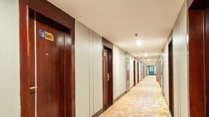 Ein Hotelgang mit Holztüren, Teppichboden und einem blauen Schild an der linken Tür.