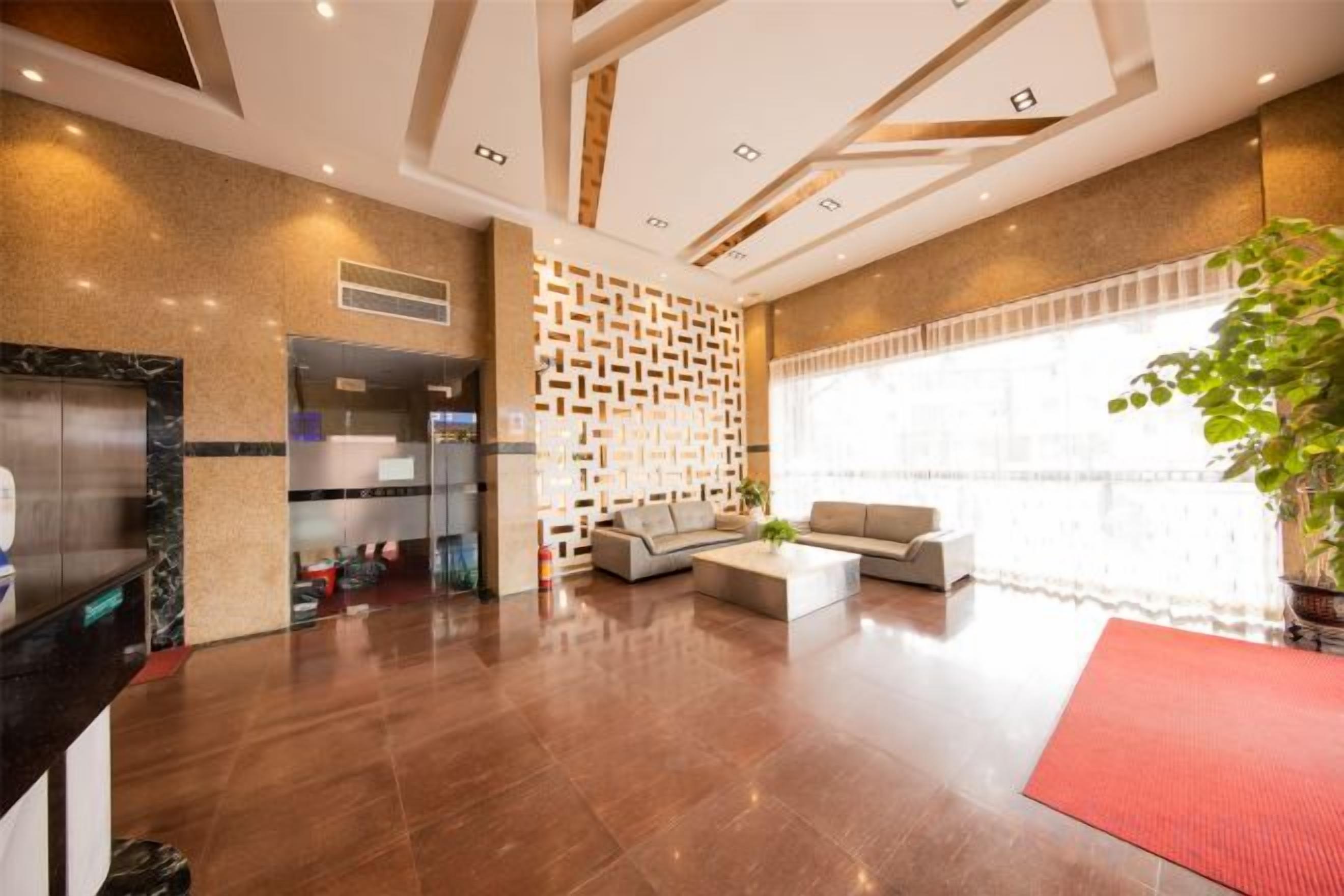 A hotel lobby with a reception desk, seating area, and a large window.