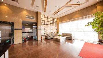 A hotel lobby with a reception desk, seating area, and a large window.