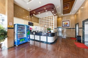 A hotel reception area with a vending machine, a reception desk, and a wall with a geometric pattern. - wonder travel hotel(kaiping dongxing) (Kaiping)
