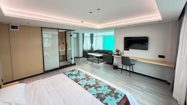 Ein modernes Hotelzimmer mit Bett, Schreibtisch, Sofa und Fernseher.