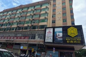A hotel building with multiple floors and a signboard advertising a hotel.