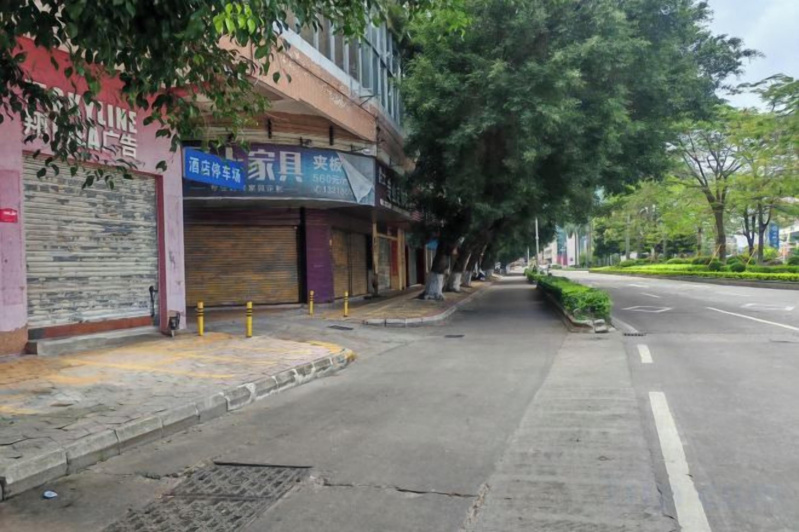 Una calle con comercios cerrados, una acera y una vía.