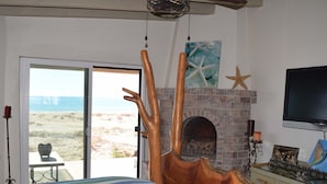 Un dormitorio con cama, chimenea, televisor y vista a la playa.