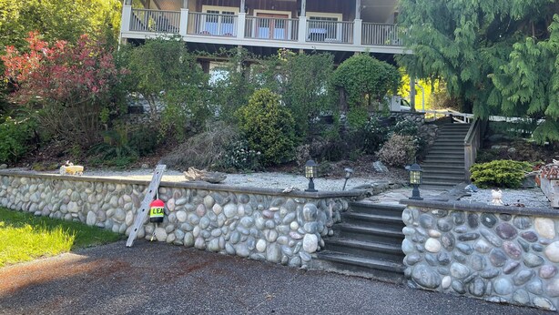 A two-story house with a stone retaining wall and a set of stone steps leading to the entrance.