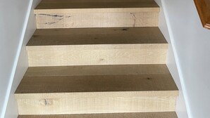 A wooden staircase with a wooden handrail and white walls.