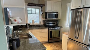 A modern kitchen with white cabinets, a stainless steel refrigerator, a microwave, and a stove.