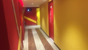 A hallway with red and yellow walls, a striped floor, and a door labeled "112". - Hotel Nayarit - Solo Adultos (Mexico City)