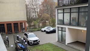Une cour avec une pelouse, des voitures garées et des vélos.