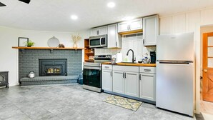 A modern kitchen with grey cabinets, a built-in microwave, a refrigerator, and a fireplace. - Modern Studio < 13 Mi to Saratoga Racetrack! (Ballston Spa)