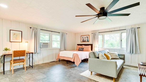 A bedroom with a bed, a desk, a chair, a ceiling fan, and large windows. - Modern Studio < 13 Mi to Saratoga Racetrack! (Ballston Spa)
