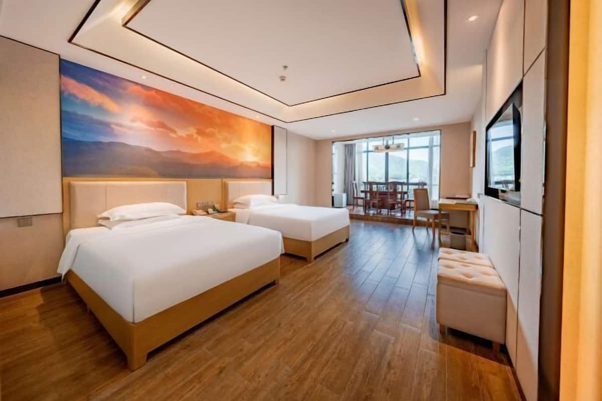Ein Hotelzimmer mit zwei Betten, einem Essbereich und einem Fernseher.