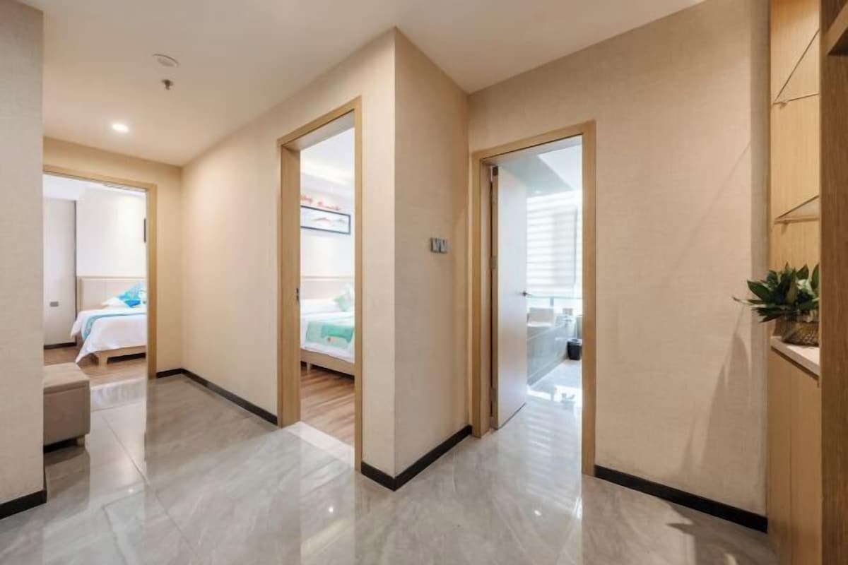 A hotel hallway with a bed, a plant, and a door leading to another room.
