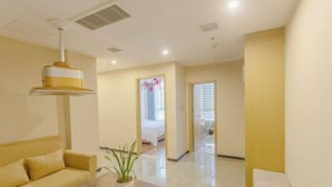 A hotel room with a sofa, a small table with a plant, a bed, and a hallway leading to another room. - Tongren Fanjingshan Shuxiang Mendi Hotel (Jiangkou County) (Jiangkou)