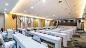 A conference room with rows of tables and chairs, equipped with ceiling lights and a large screen. - Tongren Fanjingshan Shuxiang Mendi Hotel (Jiangkou County) (Jiangkou)