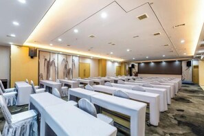 A conference room with rows of tables and chairs, equipped with ceiling lights and a large screen. - Tongren Fanjingshan Shuxiang Mendi Hotel (Jiangkou County) (Jiangkou)