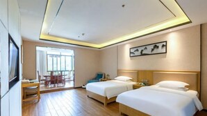 Une chambre d’hôtel avec deux lits, un bureau, une chaise, une fenêtre avec des rideaux et un tableau au mur.