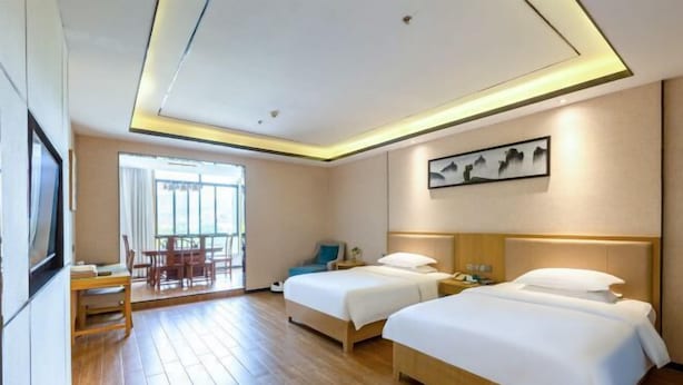 A hotel room with two beds, a desk, a chair, a window with curtains, and a painting on the wall. - Tongren Fanjingshan Shuxiang Mendi Hotel (Jiangkou County) (Jiangkou)