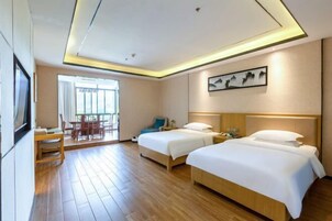 A hotel room with two beds, a desk, a chair, a window with curtains, and a painting on the wall.