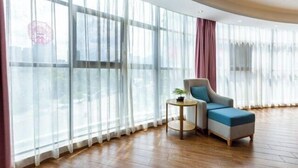 A modern room with large windows, a curved ceiling, and a blue armchair. - Tongren Fanjingshan Shuxiang Mendi Hotel (Jiangkou County) (Jiangkou)