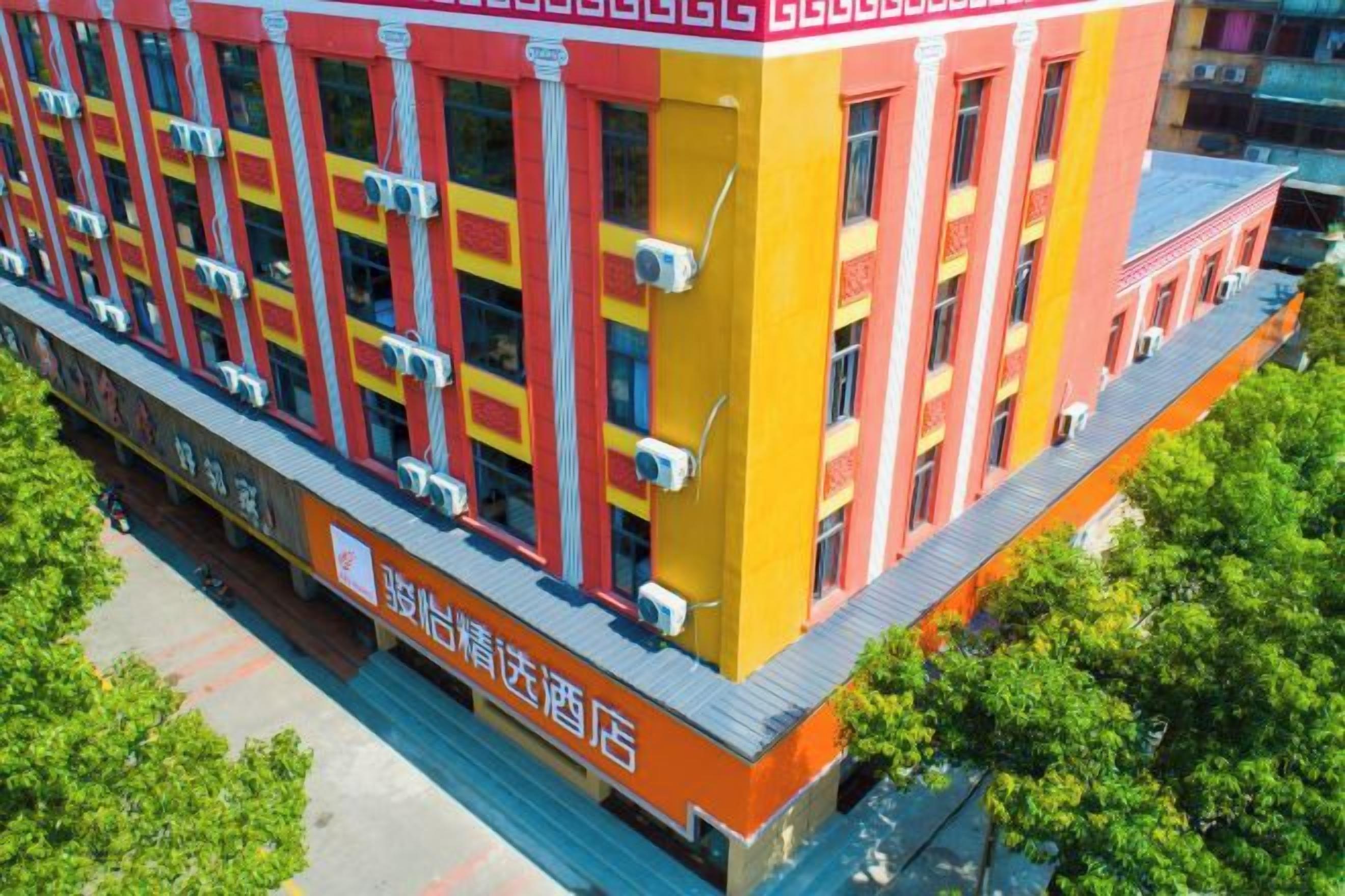 Un edificio de varios pisos con fachada roja y amarilla, ventanas amplias y unidades de aire acondicionado.