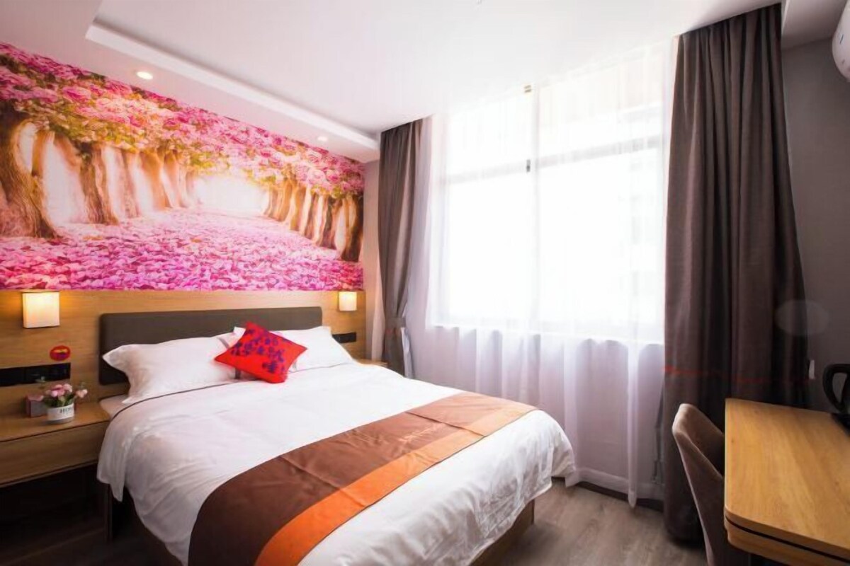 Una habitación de hotel con una cama, una mesita de noche, una silla, una mesa y un amplio mural floral.