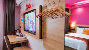 A hotel room with a TV, wooden furniture, a bed, and a wall-mounted coat rack.