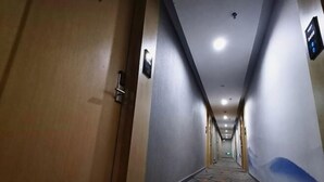 Un pasillo de hotel con una puerta de madera, piso con diseño y pared azul decorativa.