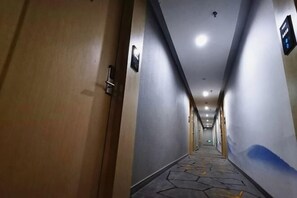 A hotel hallway with a wooden door, a patterned floor, and a blue accent wall. - Junyi Hotel (Shaoxing Shangyu Pedestrian Street) (Shaoxing)