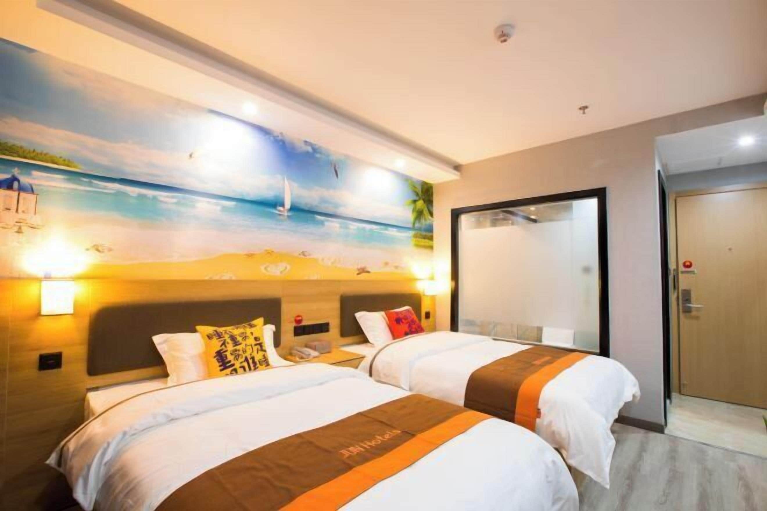 Habitación de hotel con dos camas, un mural de playa en la pared y una puerta a la derecha.