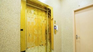 Habitación de hotel con puerta de madera, un espejo y un pequeño dispositivo fijado a la pared.