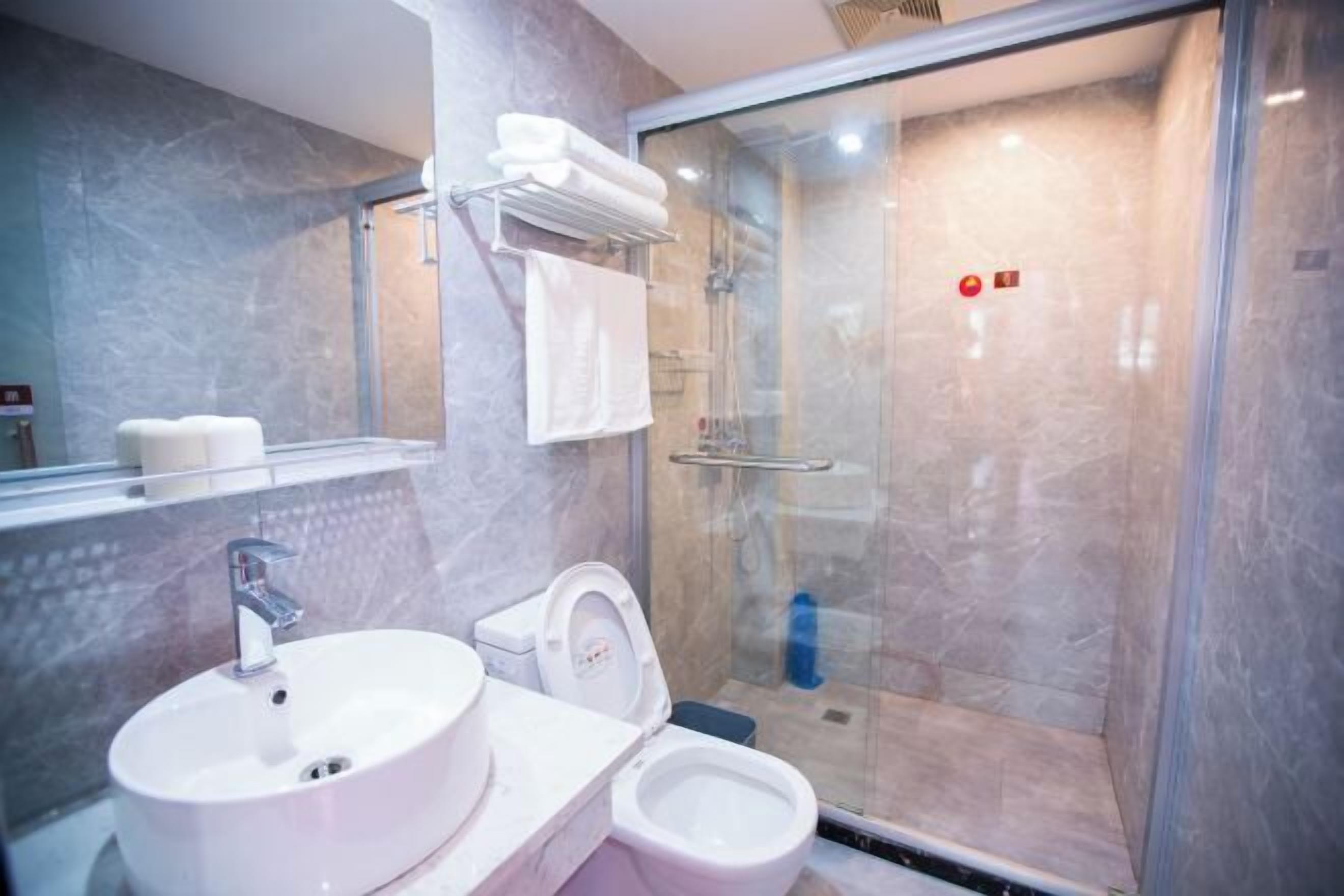 Un baño moderno con lavamanos, inodoro y ducha con mampara de vidrio.