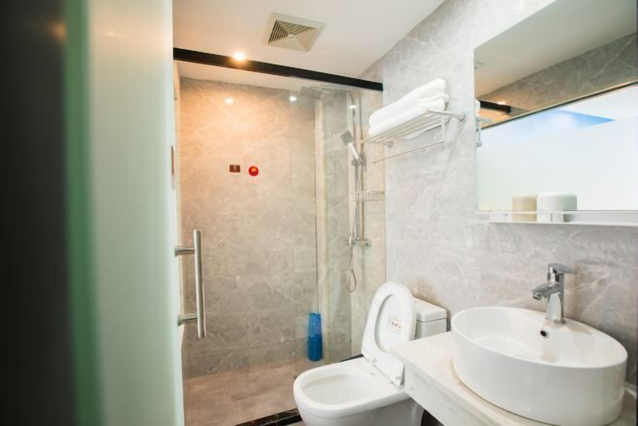 Un baño moderno con ducha de vidrio, un lavamanos blanco y un espejo sobre él.