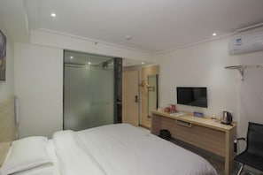Ett hotellrum med en säng, ett skrivbord med en platt-TV, en spegel och en garderob.