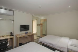 Ett hotellrum med en säng, ett skrivbord med en tv, en spegel och en garderob.