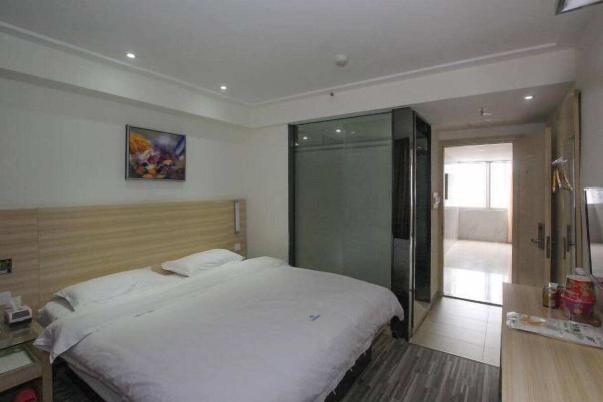 A hotel room with a bed, bedside table, and a painting on the wall.