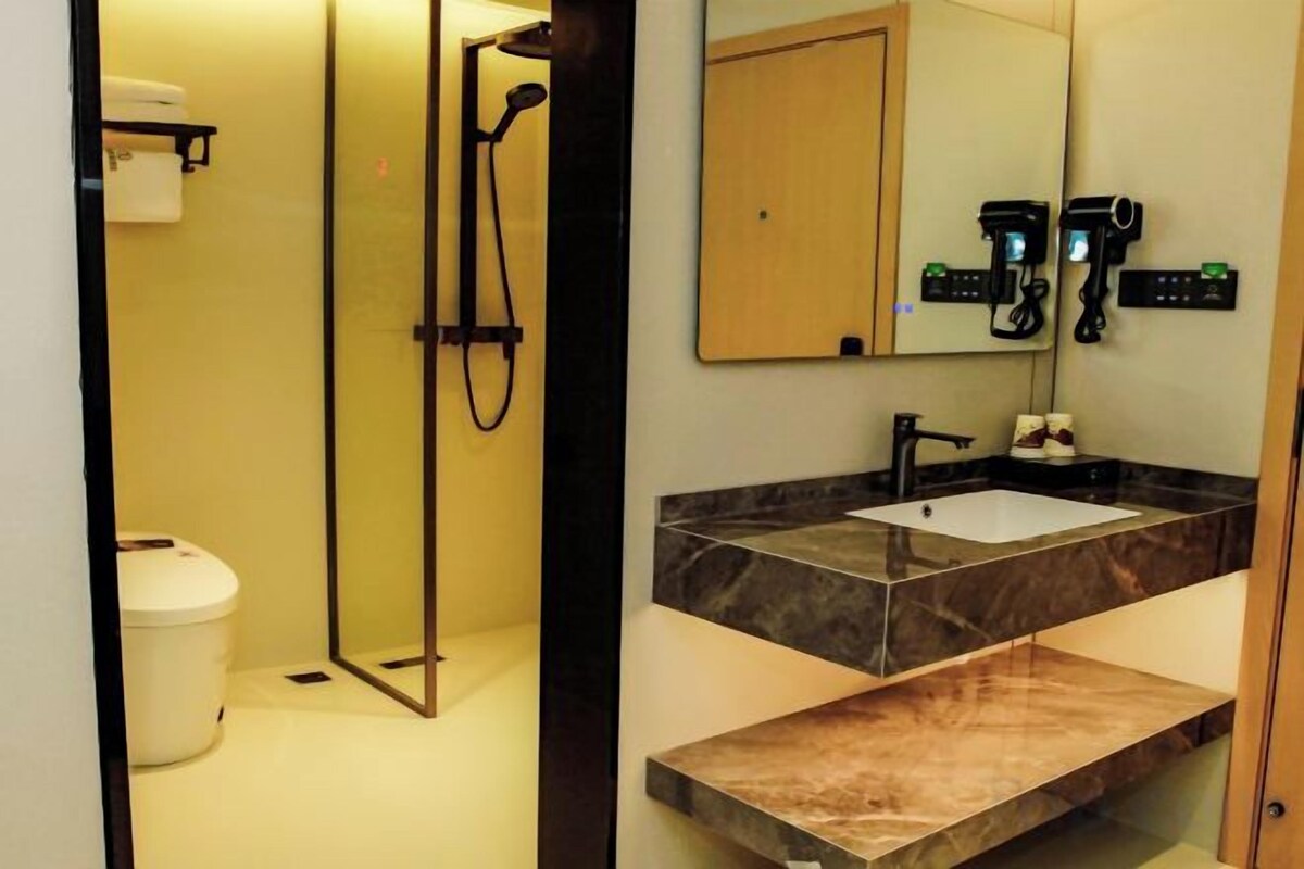 Un baño con ducha, inodoro, lavabo y espejo.