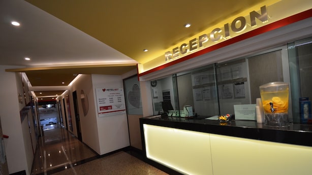 A hotel reception area with a reception desk, a glass partition, and a sign above the desk that reads "RECEPTION". - Hotel La Villa - Solo Adultos (Mexico City)