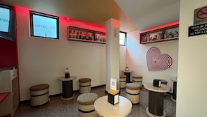 A modern hotel lobby with round wooden stools, a central pillar, and a heart-shaped wall decoration. - Hotel La Villa - Solo Adultos (Mexico City)