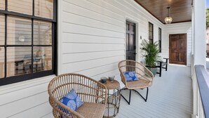 A covered porch with wicker chairs and a table, white siding, and a wooden ceiling. - The Charleston Suites: The Victoria Suite - 3bd/2ba ample outdoor space (Charleston)
