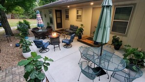Une terrasse avec des meubles d’extérieur, un foyer et des plantes en pot.