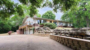 A two-story house with a covered porch, stone retaining wall, and a driveway. - Peaceful retreat, just 10 minutes outside of town (LAWRENCE)