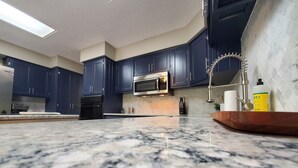A modern kitchen with dark blue cabinets, a stainless steel microwave, and a granite countertop. - Peaceful retreat, just 10 minutes outside of town (LAWRENCE)