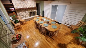 Un coin repas agrémenté d’une cheminée en pierre, d’une table à manger en bois et de chaises.
