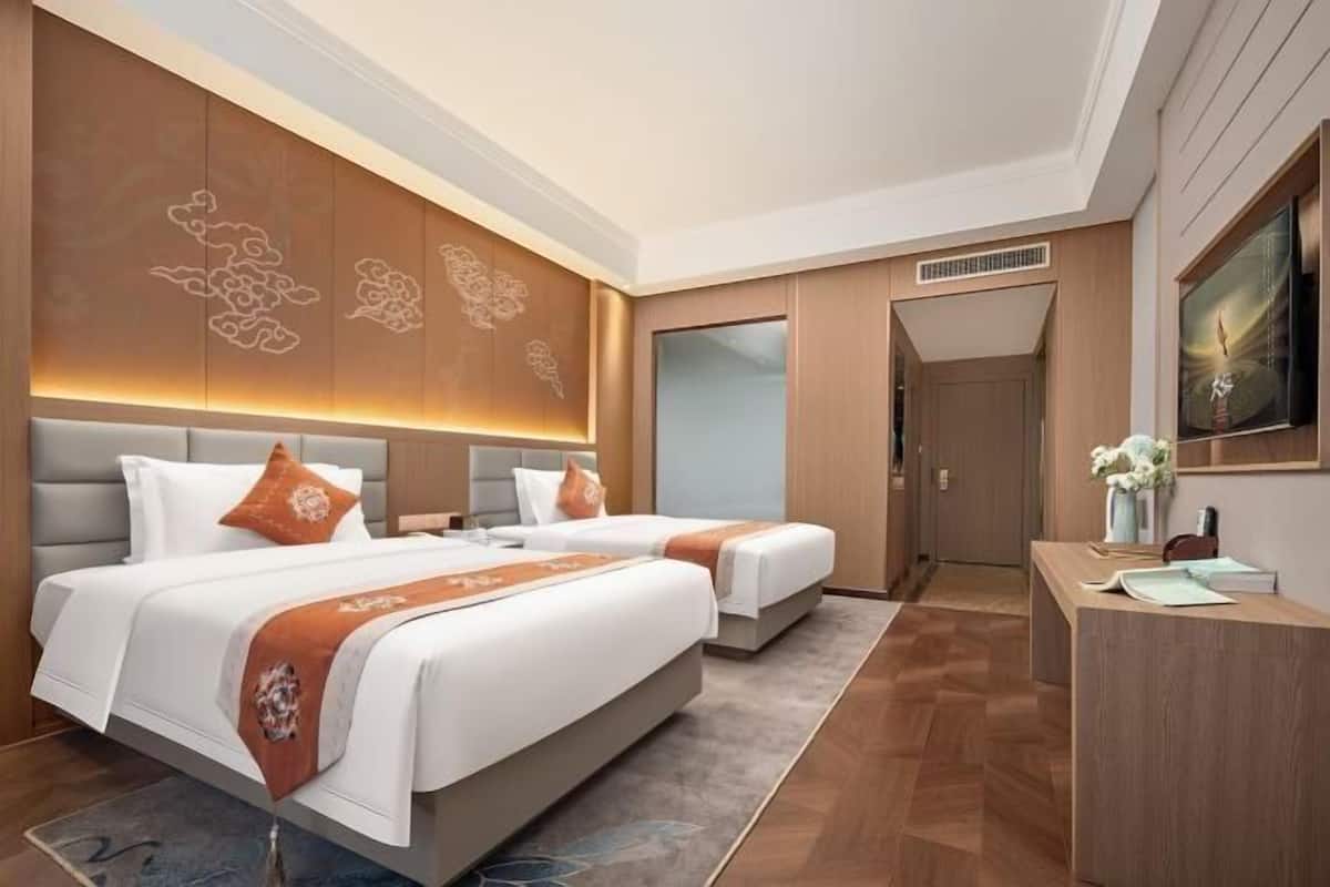 Una habitación de hotel moderna con dos camas, un escritorio y un espejo grande.
