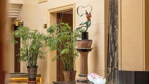 A lobby with a marble floor, potted plants, a decorative fountain, and a statue. - Yulin Hotel (Guazhou)