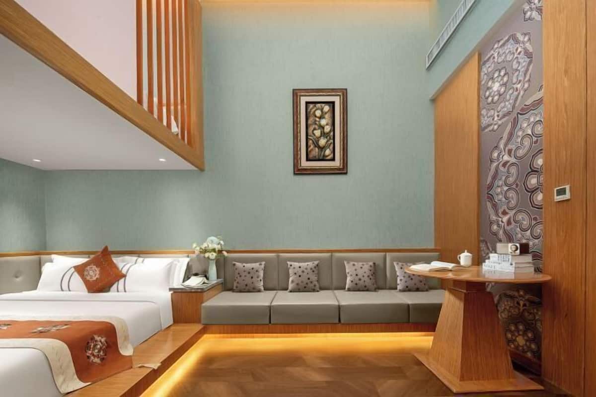 Habitación de hotel con cama, sofá, mesita de noche y una obra de arte en la pared.