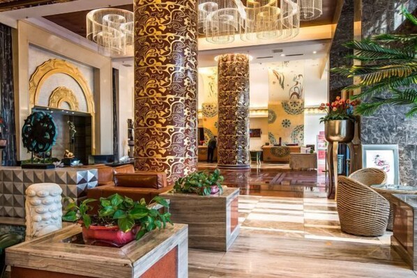 A lobby with ornate pillars, a reception desk, and a seating area with plants. - Yulin Hotel (Guazhou)