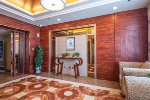 A hotel lobby with a patterned floor, a reception desk, and a seating area. - Yulin Hotel (Guazhou)